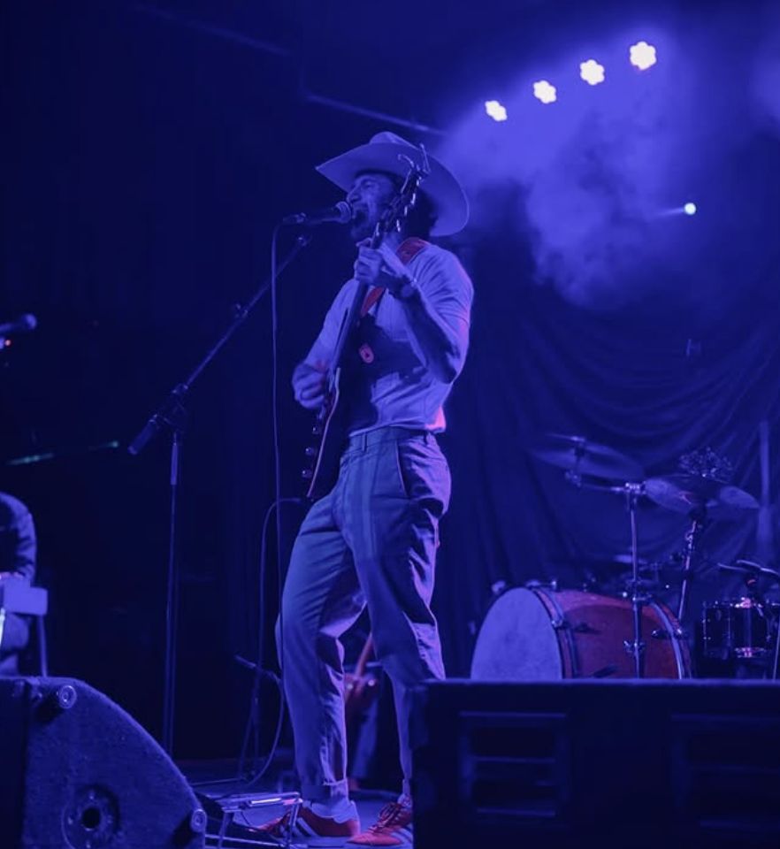 Brice Posin performing live with cowboy hat and guitar